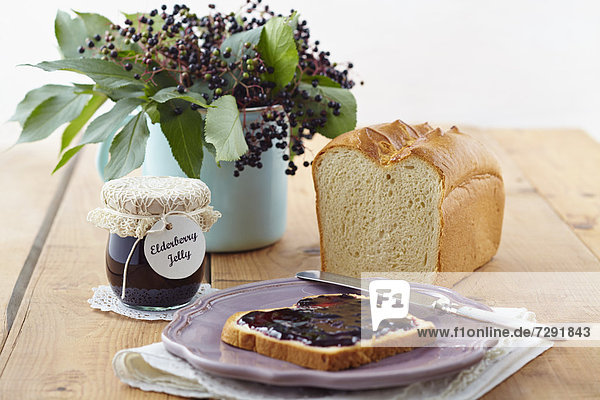Elderberry jam with white bread on wooden table