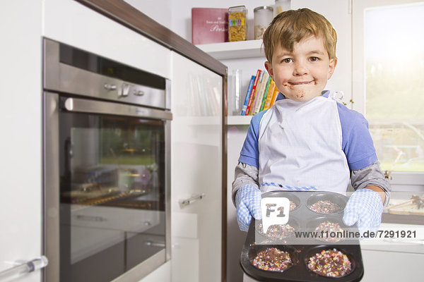 Germany  Boy baking cup cakes in tray  portrait