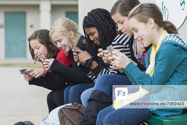 School girls text messaging on cell phones