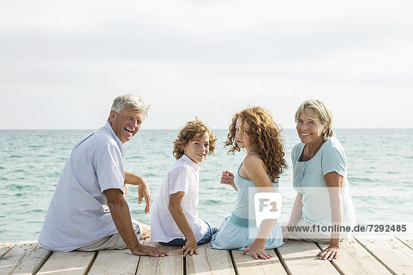 Spain  Grandparents with grandchildren sitting on jetty  smiling  portrait