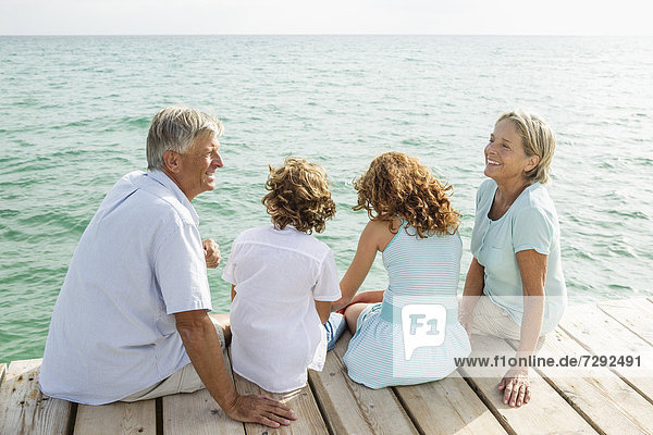 Spain  Grandparents with grandchildren sitting on jetty