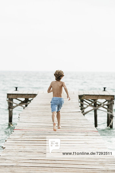 Spain  Boy running on jetty at the sea