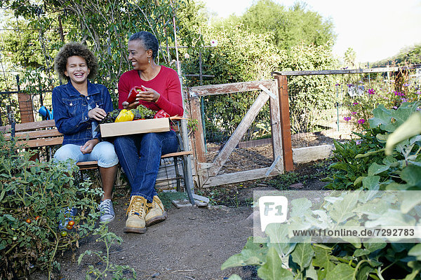 Mother and daughter gathering vegetables in community garden