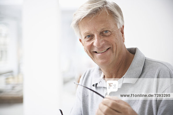 Spain  Senior man holding glasses  smiling  portrait