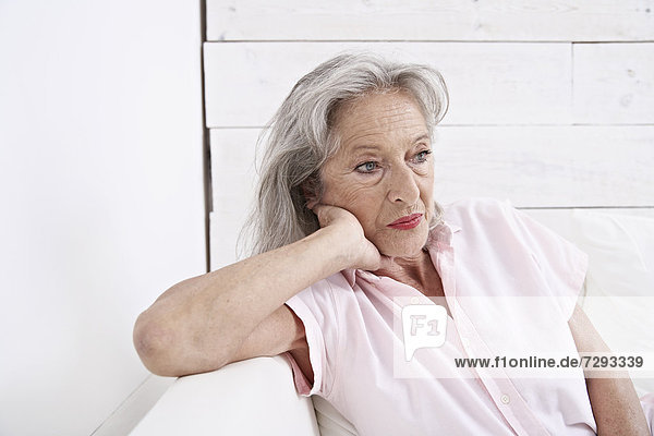 Spanien  Mallorca  Traurige Seniorin auf der Couch sitzend