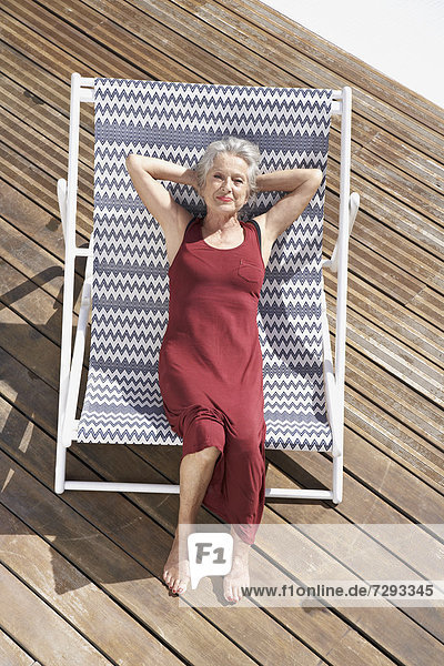 Spain,  Senior woman relaxing on deck chair at beach