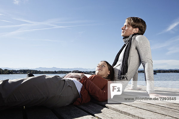 Germany  Bavaria  Couple sitting on jetty at Lake Starnberg