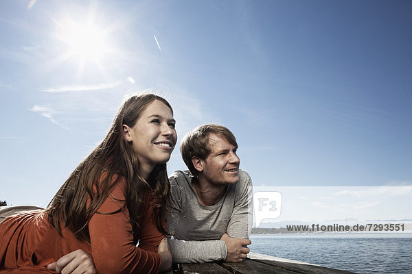 Germany  Bavaria  Couple lying on jetty at Lake Starnberg