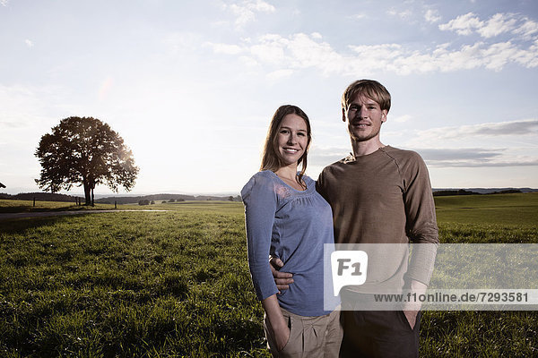 Germany  Bavaria  Couple standing in field  smiling