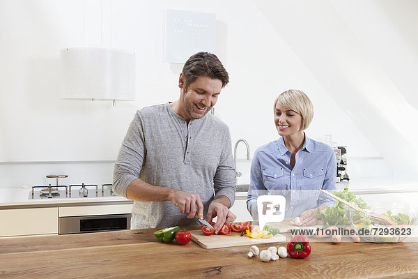 Germany,  Bavaria,  Munich,  Mature couple chopping vegetables in kitchen,  smiling