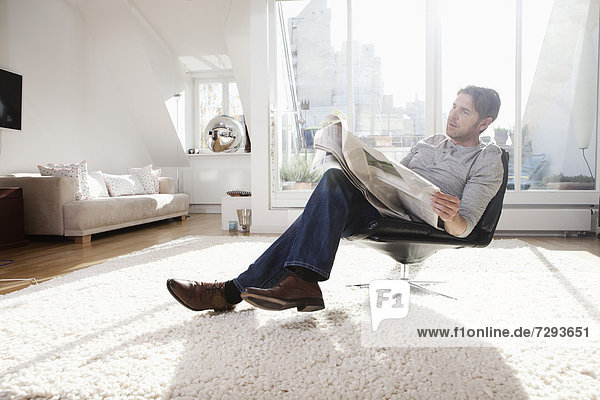 Man reading newspaper in living room