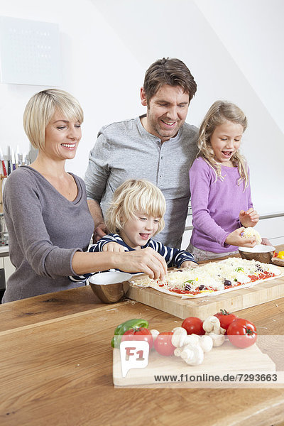 Germany  Bavaria  Munich  Family preparing pizza in kitchen