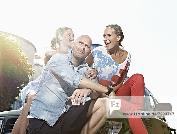 Man and women sitting on car
