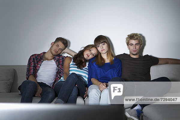 Germany  Berlin  Group of young people sitting on couch in front of screen