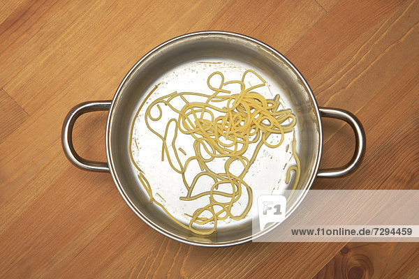 Reste von Spaghetti im Kochtopf auf Holztisch