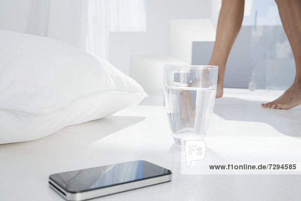 Spanien  Smartphone mit Wasserglas am Boden  Frau im Hintergrund