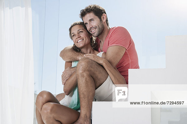 Spain  Mid adult couple sitting on stairway  smiling