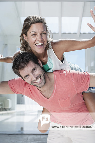 Spain,  Mid adult man giving piggy back ride to woman,  smiling