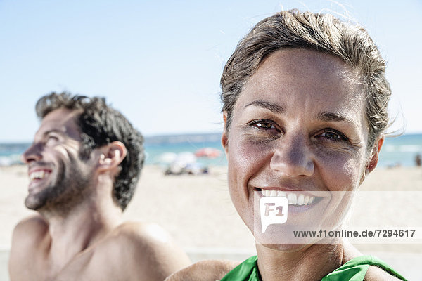 Spain,  Mid adult couple sitting at beach,  smiling