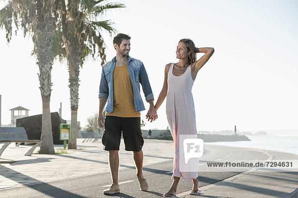 Spain  Mid adult couple walking down street  smiling
