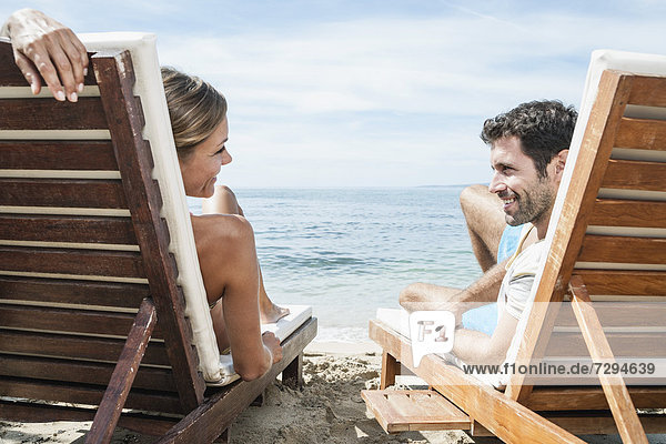 Spain,  Mid adult couple relaxing on beach chair