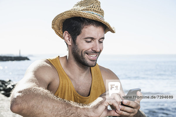Spain,  Mid adult man using smart phone,  smiling