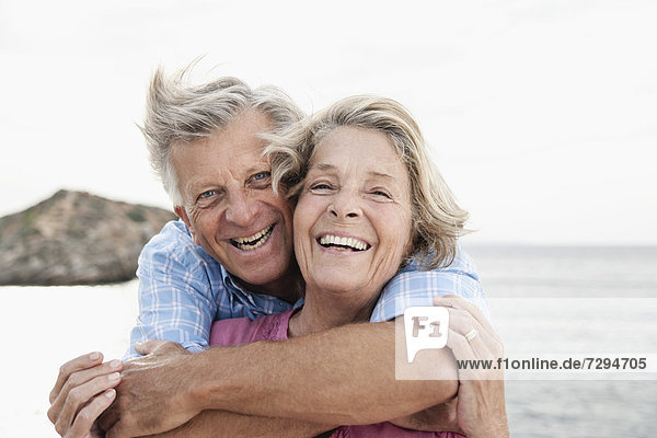 Spain  Senior couple embracing at harbour  smiling