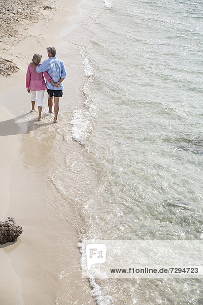 Spain,  Seniors couple walking along beach