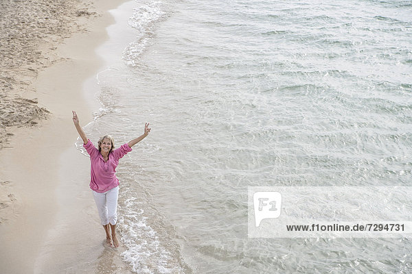 Spanien  Seniorin beim Spaziergang am Strand