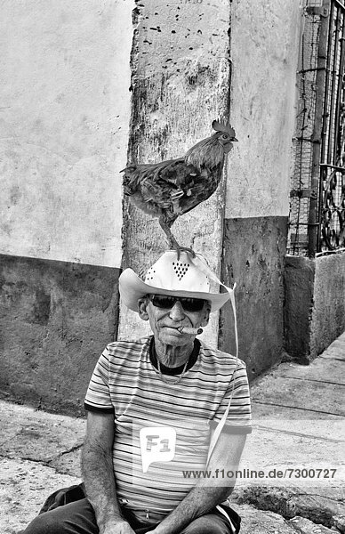 Old man with rooster on head in old Colonial village of Trinidad Cuba