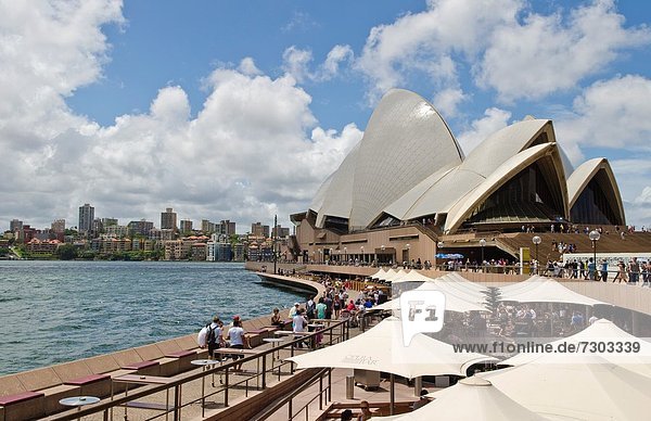Closeup of restaurant umbrellas and famous Sydney Opera House in harbour in New South Wales Australia