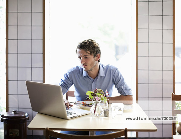 Young man at restaurant table using laptop