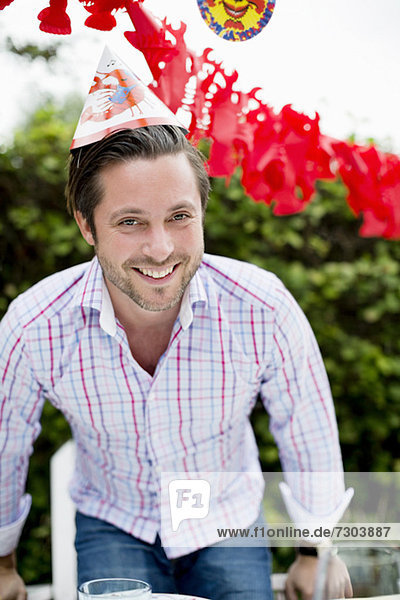 Porträt eines fröhlichen erwachsenen Mannes  der im Rasen Krebse feiert.