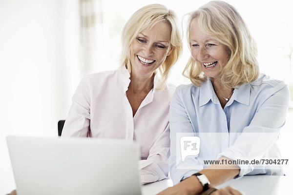 Happy businesswomen using laptop at desk in office