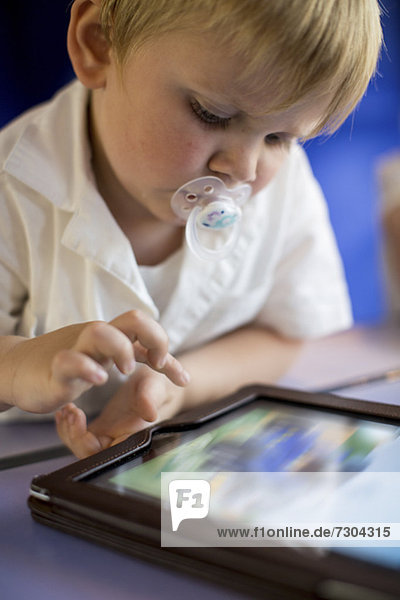 Young boy playing on digital tablet while sitting on train's seat