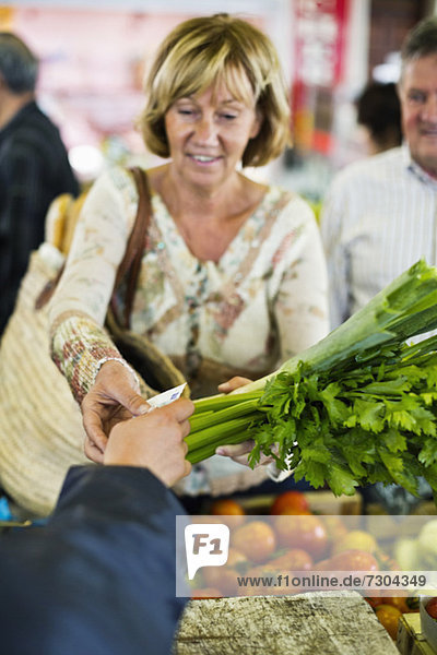 Frau bezahlt Gemüse auf dem Markt