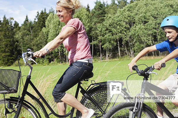 Happy mature woman and son riding bicycles during vacations