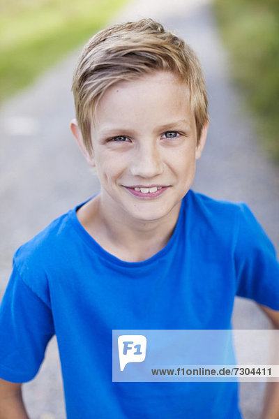 Portrait of Caucasian pre-adolescent boy standing on road smiling
