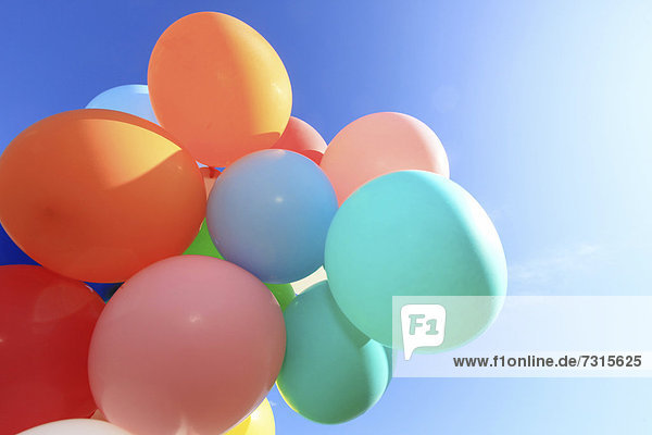 Many colourful balloons against a blue sky