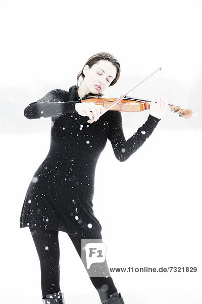 Frau  19 Jahre  mit Geige in verschneiter Winterlandschaft