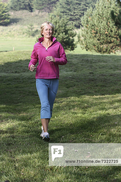 Young blonde woman outdoors. Jogging in countryside.
