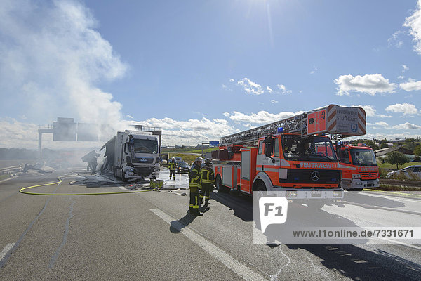 'Firefighters extinguishing a truck fire on the A8 motorway near the ''Echterdinger Ei'' junction Stuttgart Baden-Wuerttemberg Germany Europe'
