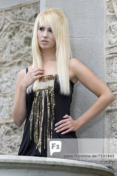 Junge Frau mit langen blonden Haaren und schwarzem Top posiert auf Empore