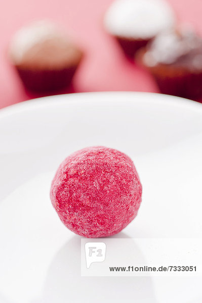 Closeup of a red chocolate truffle on a white plate