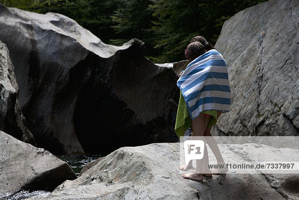 Zwei Kinder in Handtücher gehüllt und auf Felsen stehend