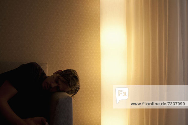 Man lying on couch beside glowing electric light