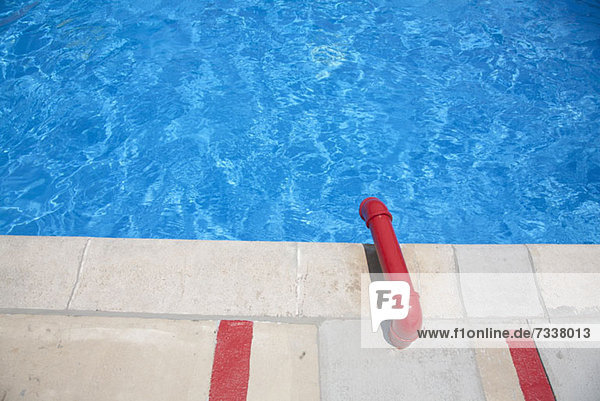 A swimming pool with a red water pipe