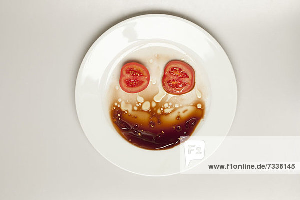 Abstraktes Gesicht aus Tomaten  Teller und Balsamico-Essig