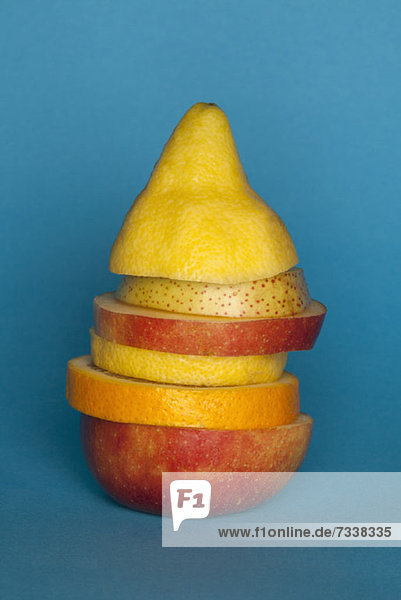 Uneven slices of different fruit stacked to comprise the shape of a piece of fruit
