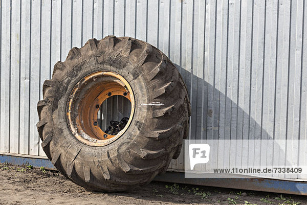 Construction vehicle wheel leaning against industrial building